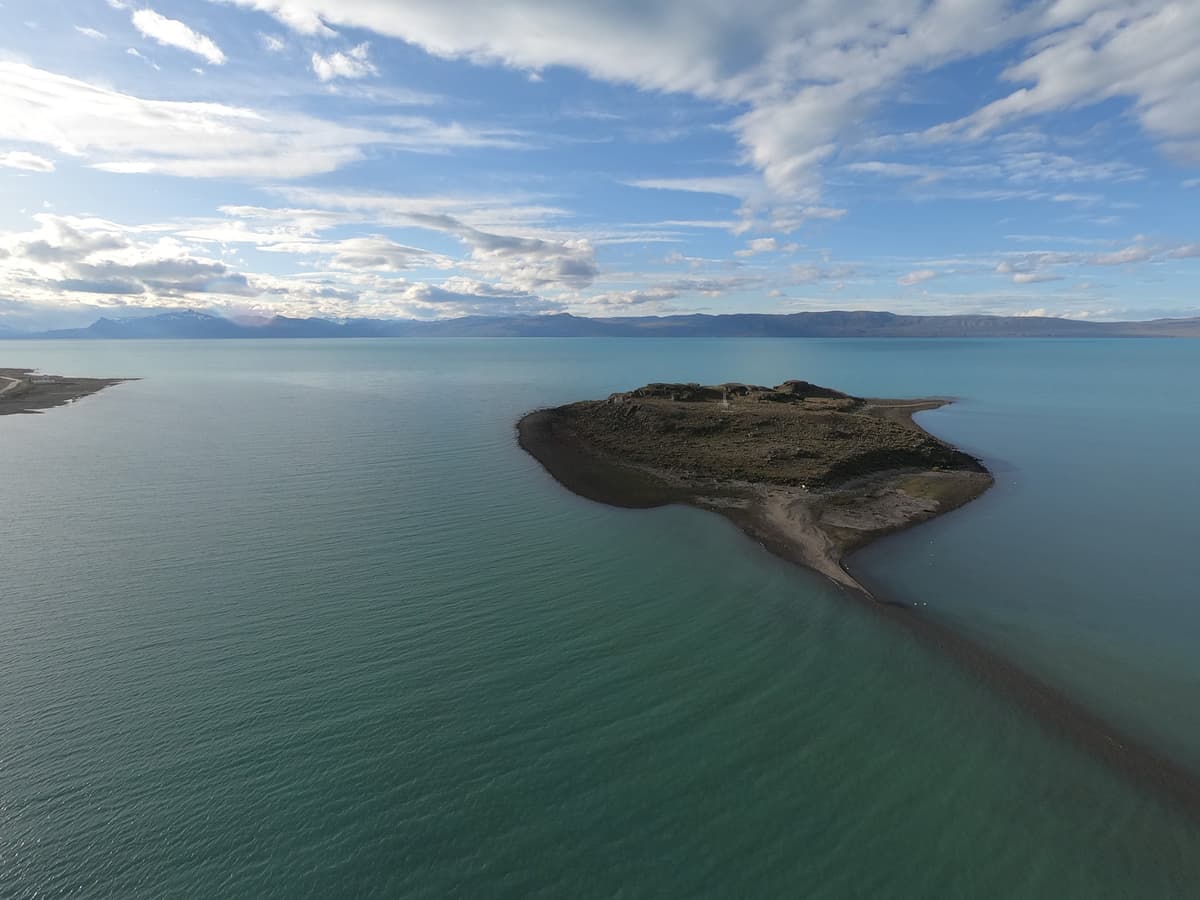 Isla Solitaria vista desde la costanera de El Calafate al atardecer, con las montañas nevadas de fondo