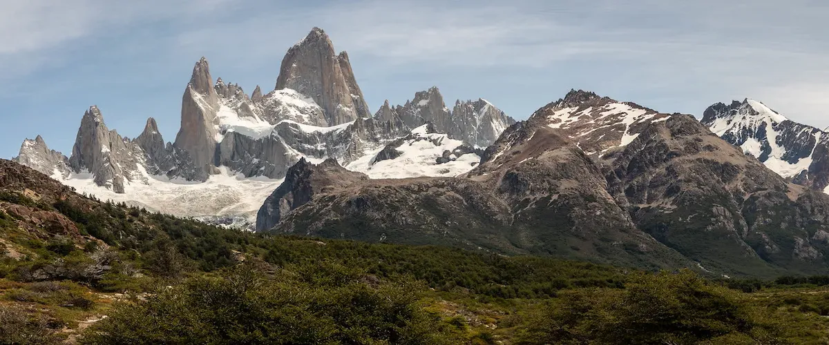 View of Mount Fitz Roy with snow-capped peaks and blue sky from the trail in El Chaltén