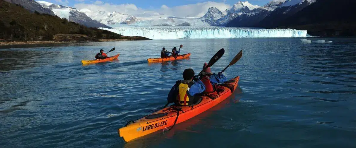 Kayakers paddling among blue ice floes in front of the Perito Moreno Glacier wall